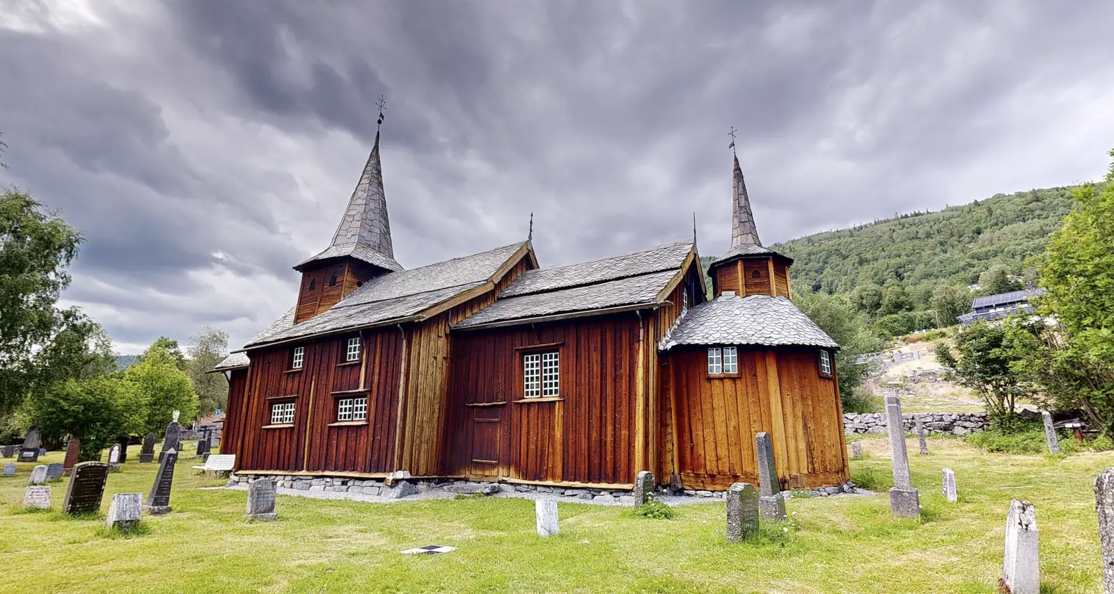 Hol gamle kyrkje sett frå kyrkjegarden, med tårn og apsis i tjørebreidd tømmer